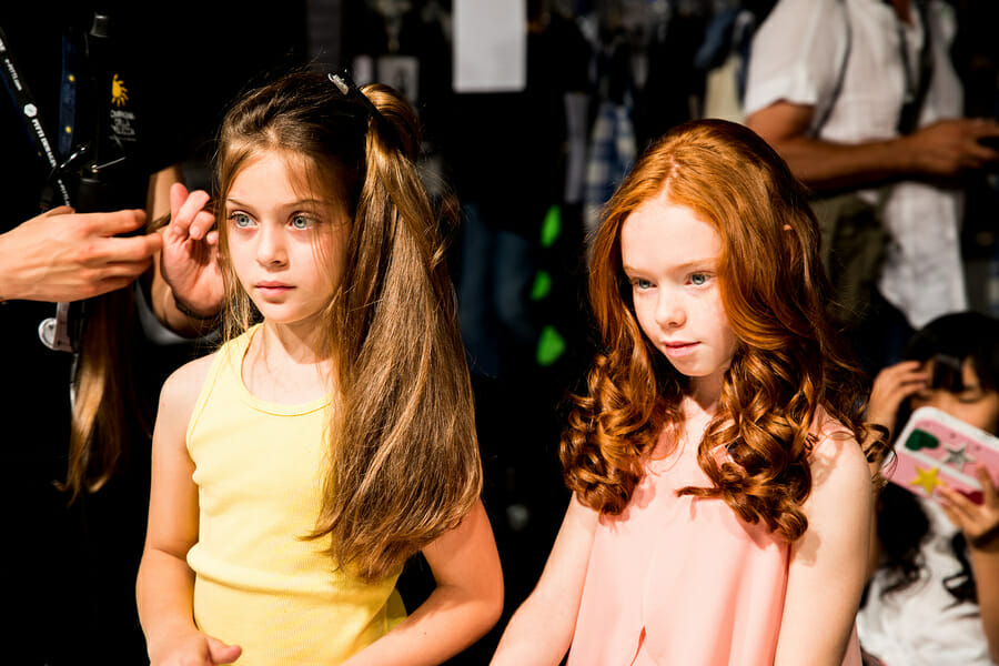 Two young models at Pitti Bimbo 87 KidsFizz show waiting on hair and make up