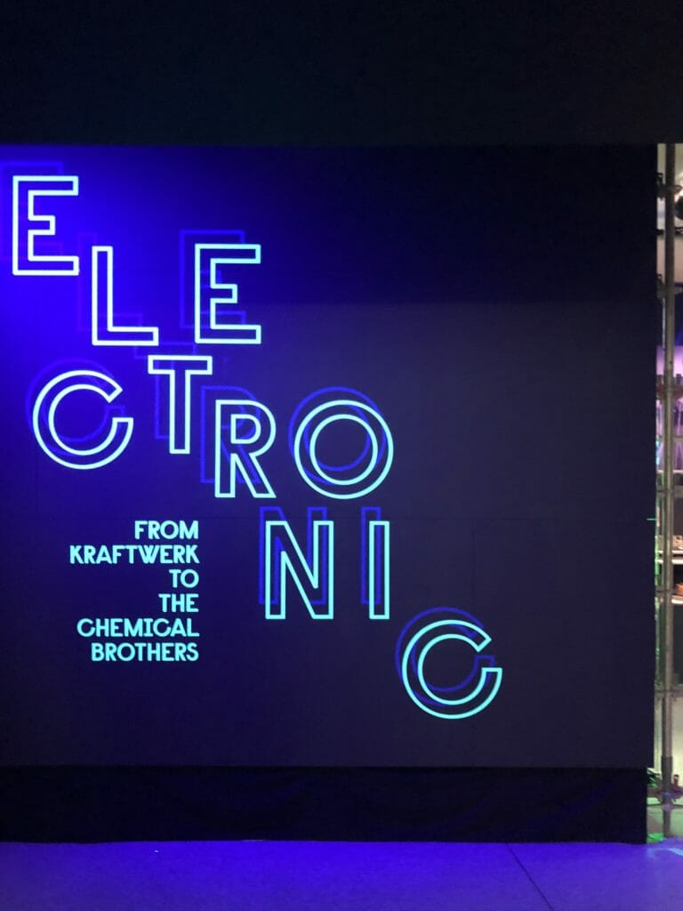A cool blue neon wall at the entrance to Electronic: From Kraftwerk to The Chemical Brothers
