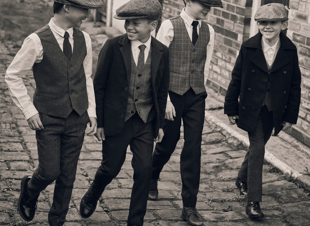 Left to right, Waistcoat, trousers, tie and hat by Paisley of London, shirt by Hugo Boss. Navy Blazer by Mayoral, waistcoat, trousers & tie by Paisley of London shirt by Paul Smith. Waistcoat, trousers & tie by Paisley of London Shirt by Hugo Boss. Coat by Hugo Boss Blazer & trousers by Paisley of London Shirt by Carrément Beau All other hats and vintage footwear by The Costume Dept.